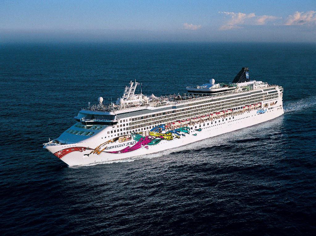 A Norwegian Jewel Class cruise ship sailing on calm waters, showcasing its elegant design and intimate size